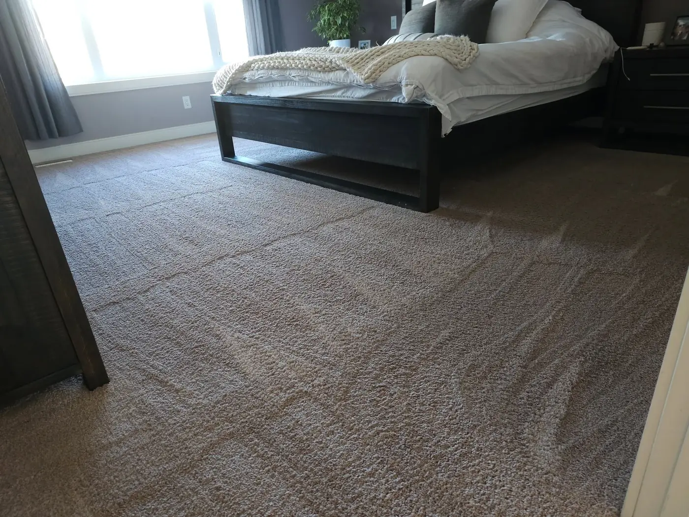 A bright bedroom with freshly cleaned carpet at the foot of the bed