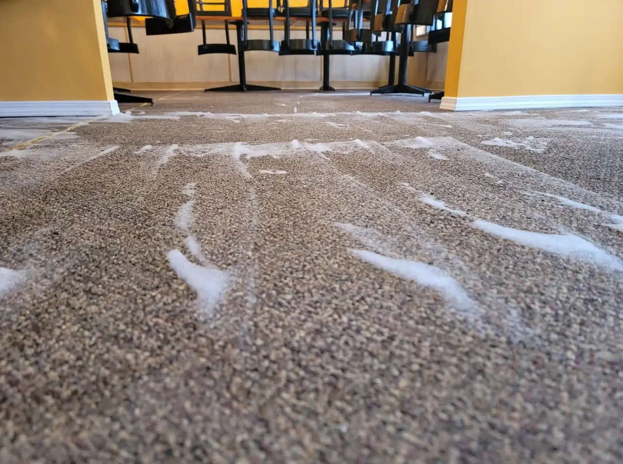 Cleaning foam on a restaurant carpet mid-clean, with the chairs lifted onto the tables